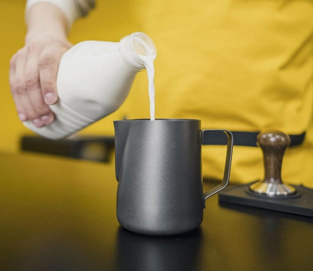 male barista pouring milk